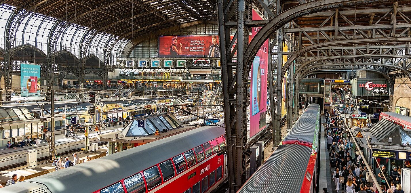 Hamburger Hauptbahnhof Der Hamburger Hauptbahnhof. Von oben sieht man das Treiben in der Bahnhofshalle mit roten Zügen und überfüllten Bahnsteigen.