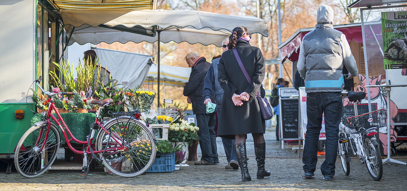 bv_Mit dem Rad zum Einkauf Marktszene mit Fußgängern und geparkten Fahrrädern