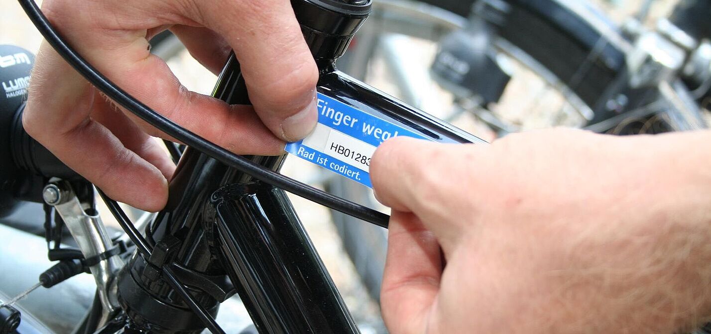 Eine Person klebt eine Codierung auf einem Fahrrad an